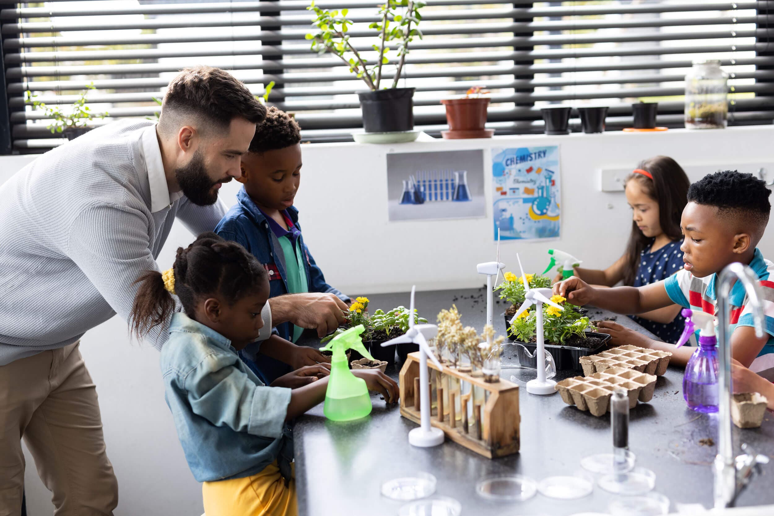 A teacher and four children potting marigold seedlings at a science bench