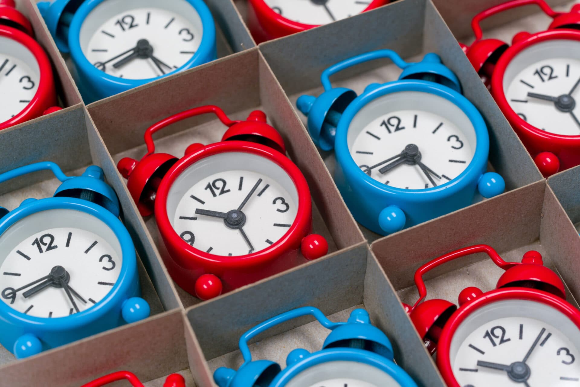 Rows of small red and blue alarm clocks arranged in a divided box