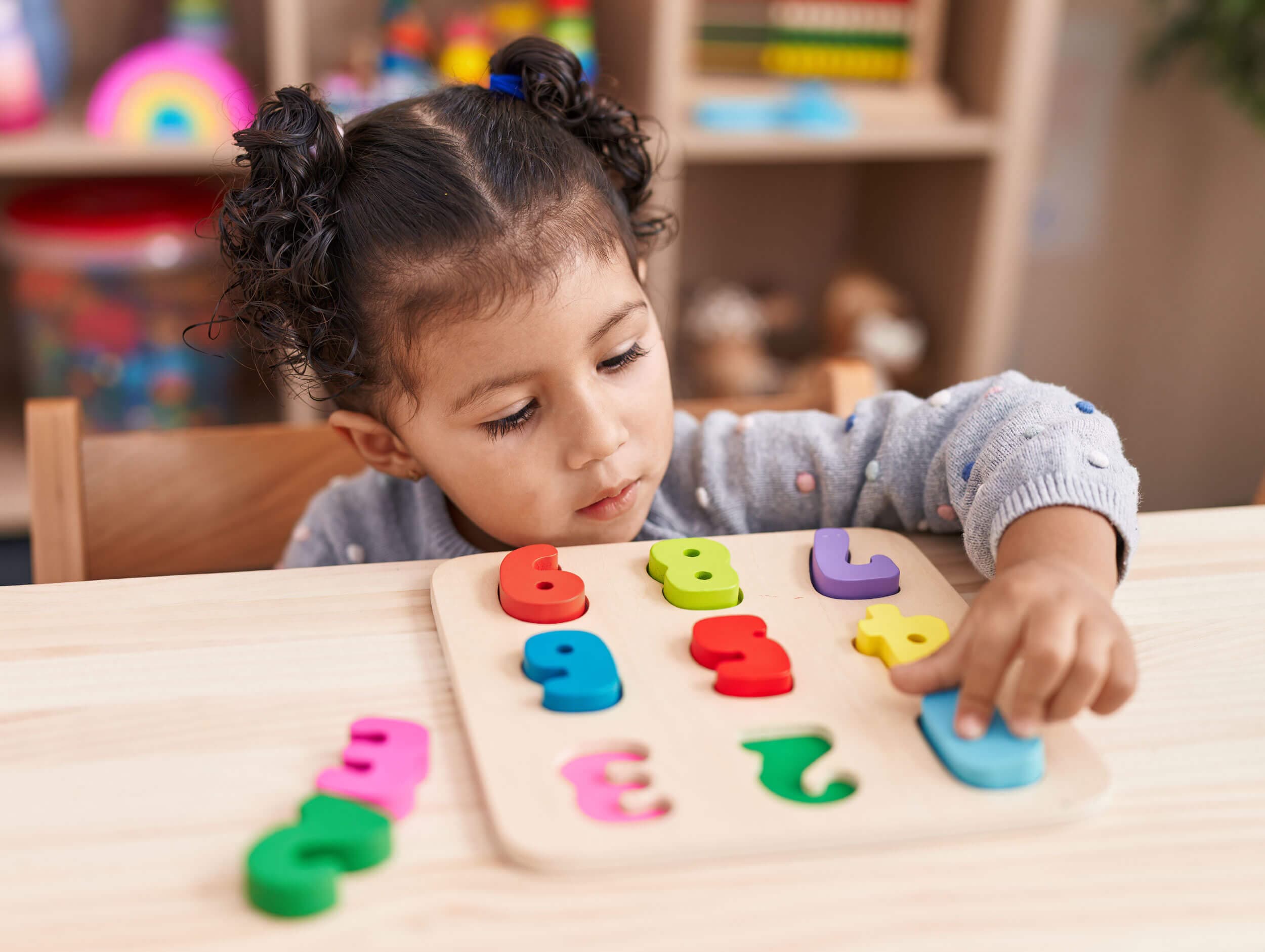 A child fitting brightly colored wooden number tiles into a counting puzzle board