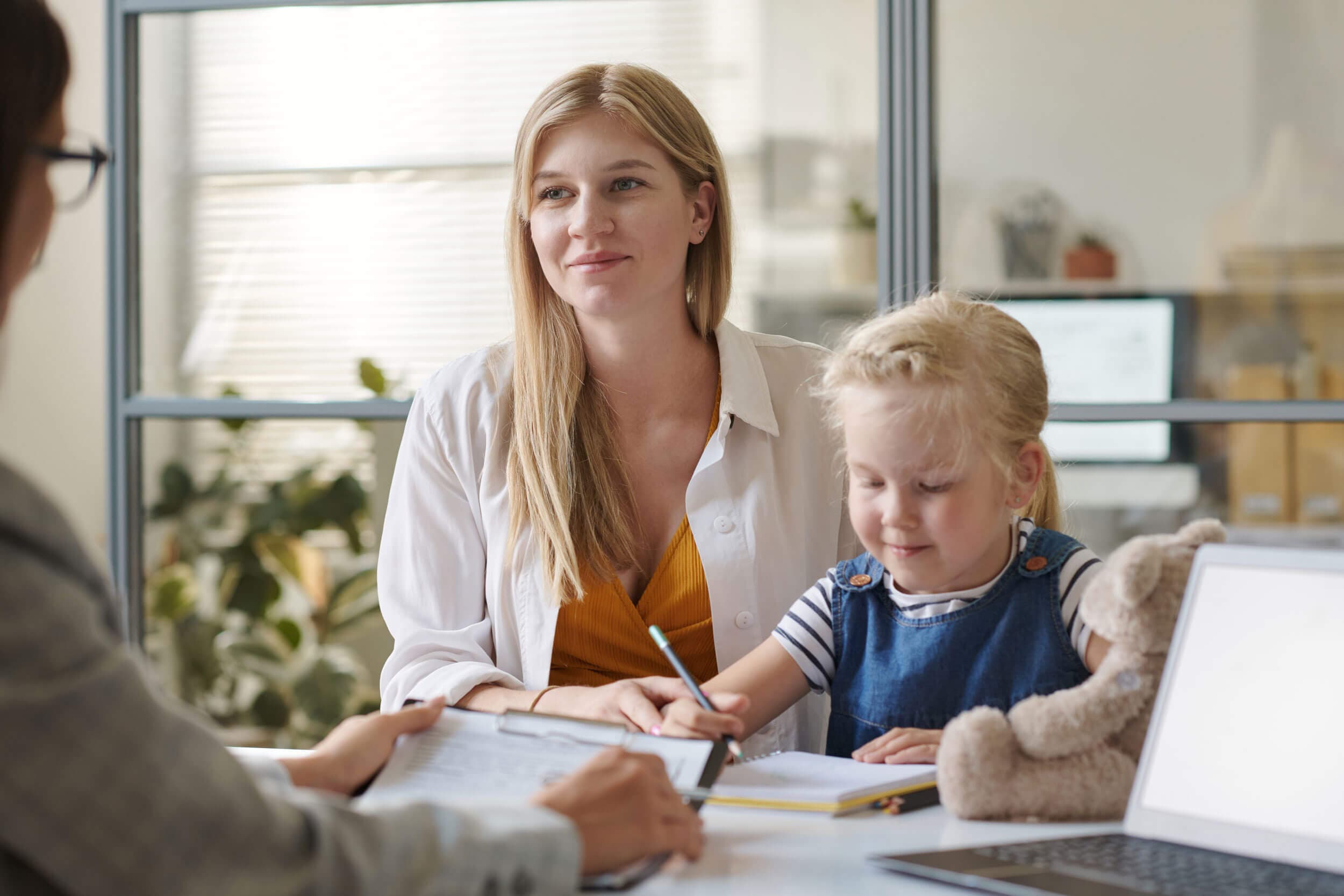 A parent and child reviewing progress notes with a teacher