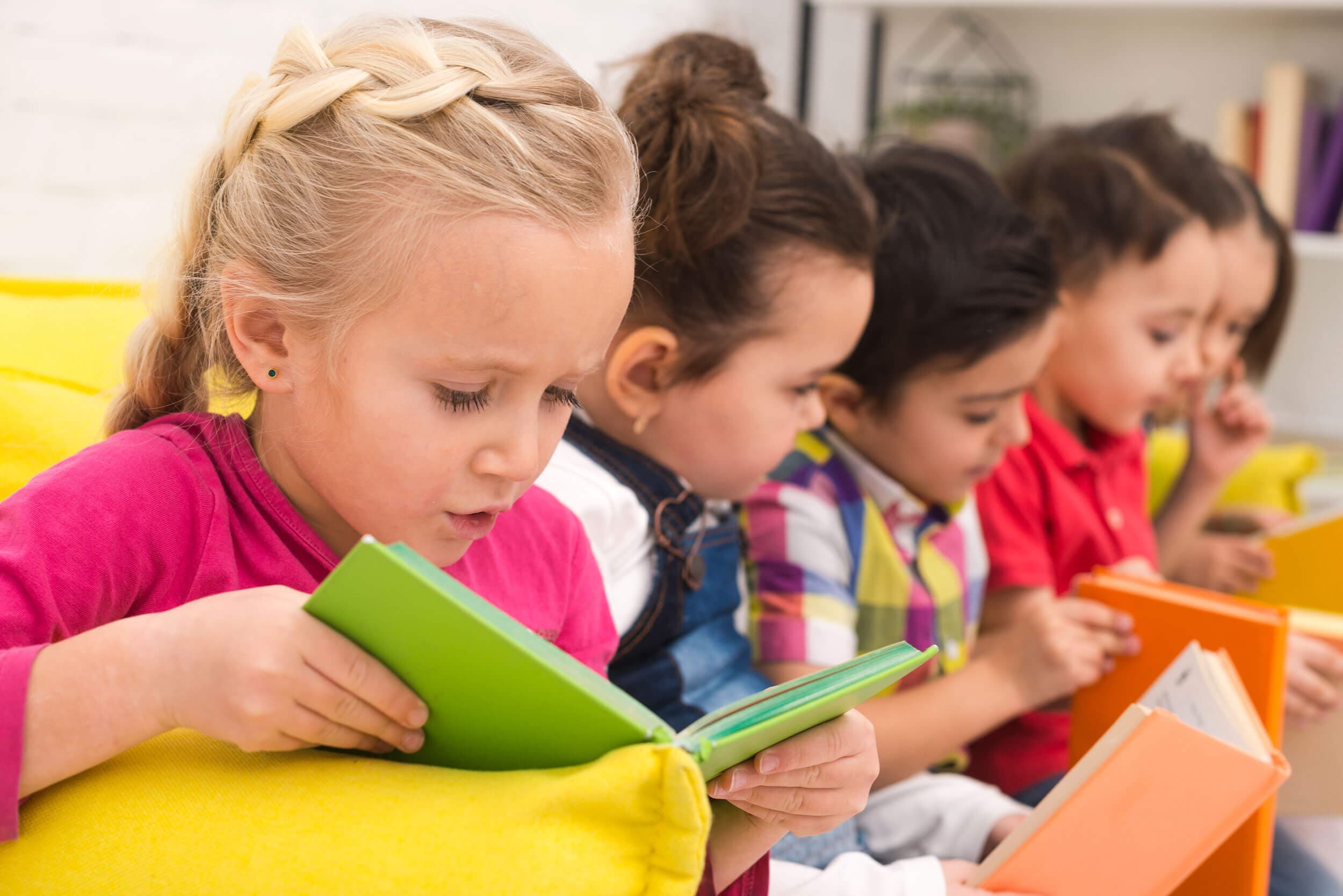 A row of children each absorbed in reading their own colorful hardcover book